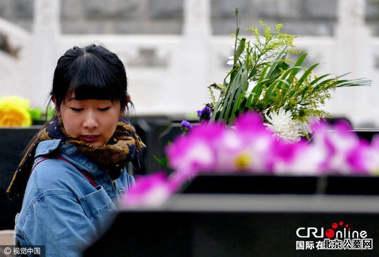 2016年04月02日，在北京通惠陵园，市民手捧鲜花为已故亲人扫墓。图片来源:李文明/视觉中国